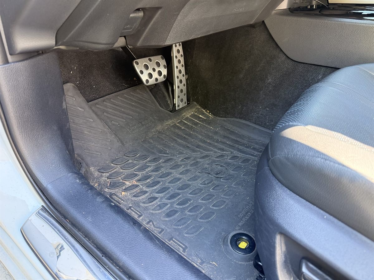 Camry driver's footwell before detailing: rubber floor mat covered in dirt, sand and leaf debris