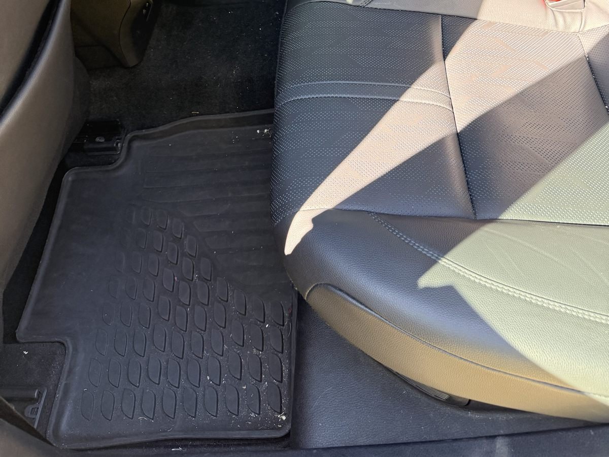 Camry rear seat and floor mat before detailing, with crumbs and debris on the mat